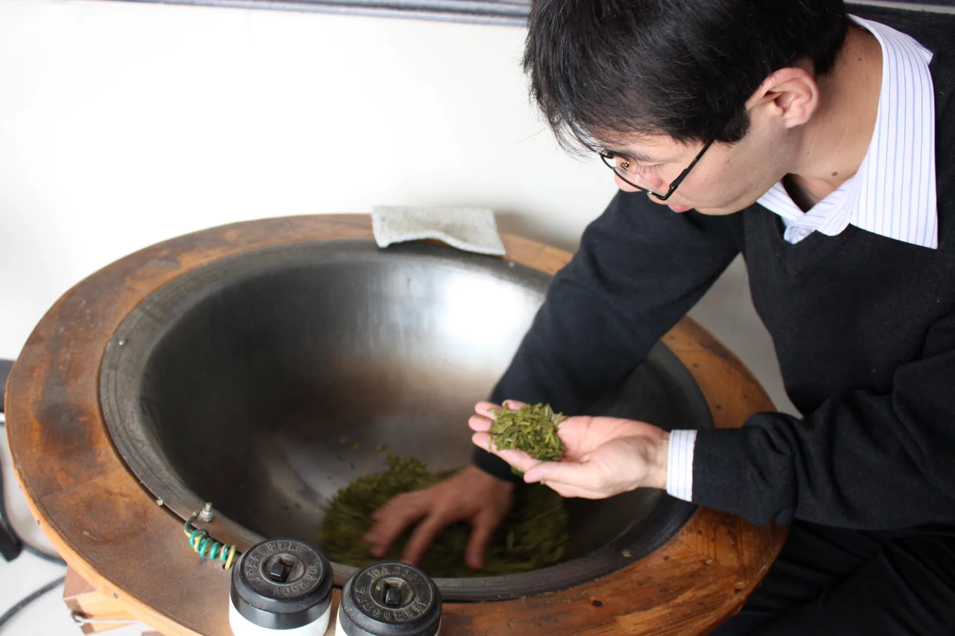 大きな釜で茶葉の加工工程を確認する大高勇気