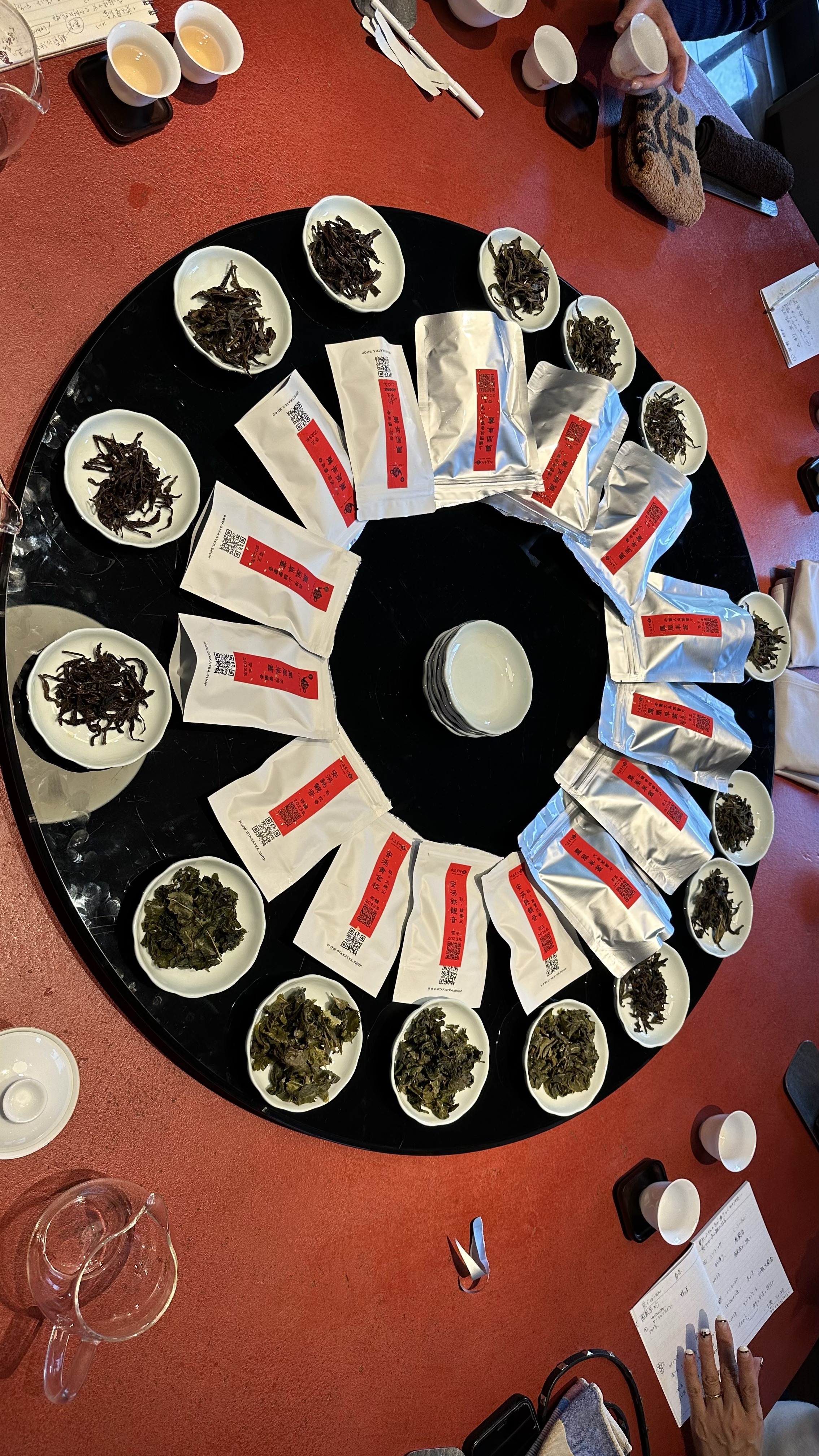 円卓に多種類の茶葉と袋が並ぶ比較試飲の全景